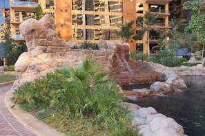 A landscaped area with a rock formation and a small water feature, surrounded by greenery and a building with balconies in the background. - bnbme Luxury Seaview Retreat with Private Beach (Dubai)