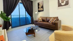 A modern living room with a brown leather sofa, a glass coffee table, and a large window with curtains. - Elegant 3-Bedroom Fully Air-Con @ Vista Sentul (Kuala Lumpur)