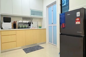 A compact kitchen with a refrigerator, microwave, and knife block.