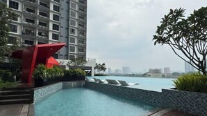 A modern building with a rooftop pool, surrounded by greenery and a red sculpture. - Elegant 3-Bedroom Fully Air-Con @ Vista Sentul (Kuala Lumpur)