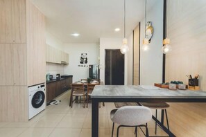 Une cuisine moderne avec des meubles en bois, un coin repas comprenant une table et des chaises, et un lave-linge.