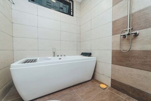 A modern bathroom with a freestanding bathtub, a showerhead, and a window. - Molek Little Joy Studio 4pax Bathtub with Balcony (Plentong)