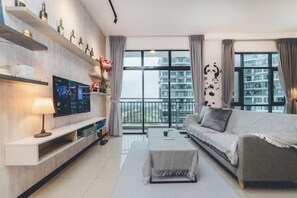 Un salon moderne doté d’un téléviseur à écran plat, d’un canapé et d’un balcon offrant une vue sur la ville.
