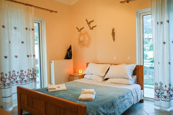 Una camera da letto con un letto, tende, un comodino e un elemento decorativo al muro.