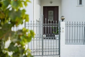Un cancello con una porta scura, una recinzione in metallo e un lampione sferico.