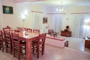 A dining area with a wooden table and chairs, a sofa, and a cabinet. - Villa Mykines (Mykines)