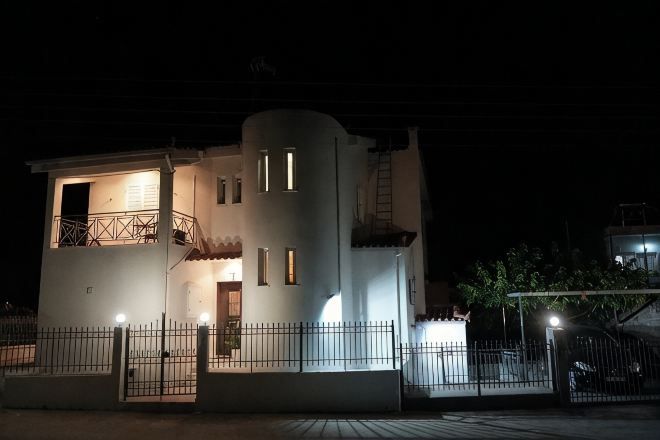 Un edificio bianco con un balcone, una scala e un ingresso recintato di notte.