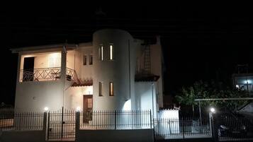 Un edificio bianco con un balcone, una scala e un ingresso recintato di notte.