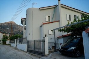 A residential building with a white facade, a red-tiled roof, and a black car parked in front. - Villa Mykines (Mykines)