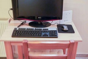 A computer setup with a monitor, keyboard, mouse, and mouse pad on a wooden desk. - Villa Mykines (Mykines)