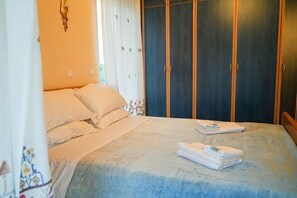 A bedroom with a bed, a wardrobe, and a window with curtains. - Villa Mykines (Mykines)