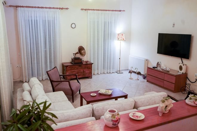 A living room with a sofa, a coffee table, a television, and a small cabinet.