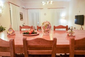 A dining area with a wooden table, chairs, a vase, and a plate of fruit. - Villa Mykines (Mykines)