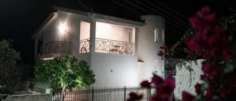 A two-story building with a balcony, a tree in front, and a fence.