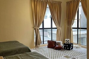 A room with two beds, a window with curtains, a small table with dice, and a view of the outside. - Happiness Stay (20 Pax) With Karaoke, Snooker, Mahjong Table (Ipoh)
