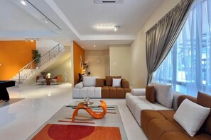 A modern living room with a sofa, a coffee table, and a staircase leading to another level. - Happiness Stay (20 Pax) With Karaoke, Snooker, Mahjong Table (Ipoh)