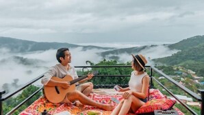 A couple sitting on a balcony with a guitar, overlooking a mountainous landscape with mist. - Mon Sa Kiang Dao (Mae Rim)