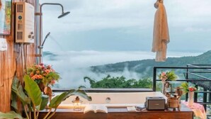 A room with a large window overlooking a mountainous landscape, a wooden desk with a lamp, and a small radio. - Mon Sa Kiang Dao (Mae Rim)
