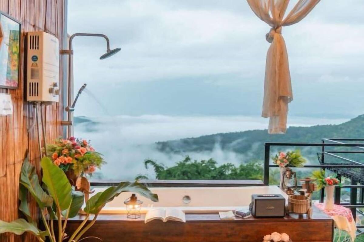 A room with a large window overlooking a mountainous landscape, a wooden desk with a lamp, and a small radio.