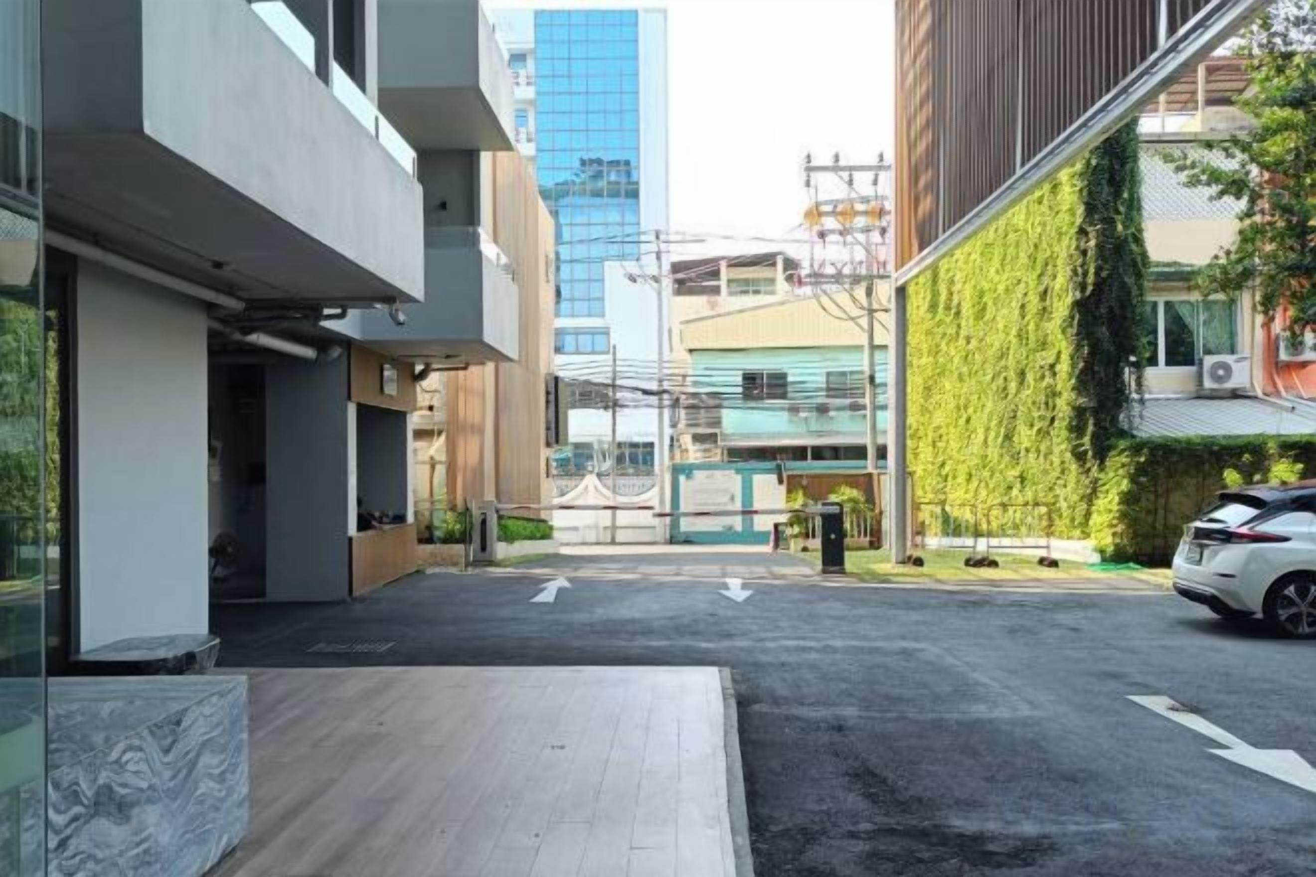 Un edificio moderno con techo plano, camino pavimentado y un coche estacionado.