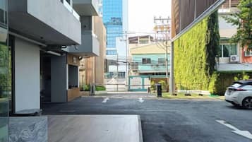 Un edificio moderno con techo plano, camino pavimentado y un coche estacionado.