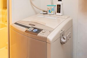 A front-loading washing machine with a control panel, a bottle of detergent, and a cup. - SkyTree View - CoCoHouse Asakusa (Tokyo)