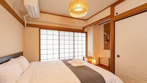 A hotel room with a large bed, a window with a view, a bedside table with a lamp, and a wardrobe. - SkyTree View - CoCoHouse Asakusa (Tokyo)