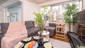 A modern living room with a sofa, dining table, and a potted plant. - SkyTree View - CoCoHouse Asakusa (Tokyo)