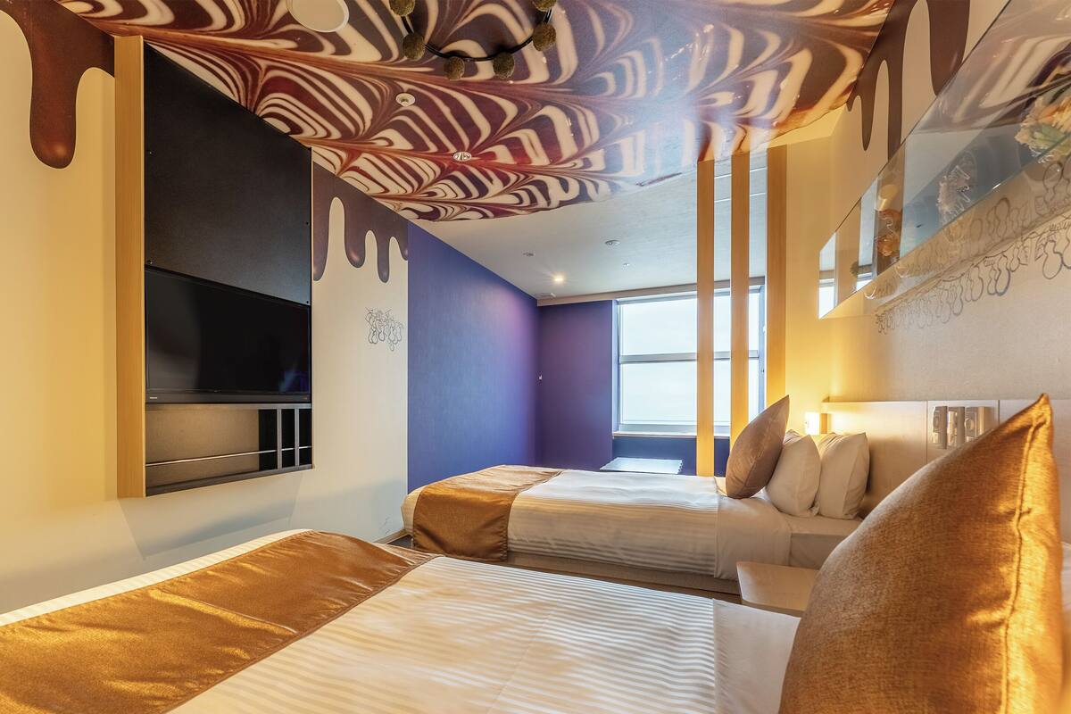 A hotel room with two beds, a TV, and a window.