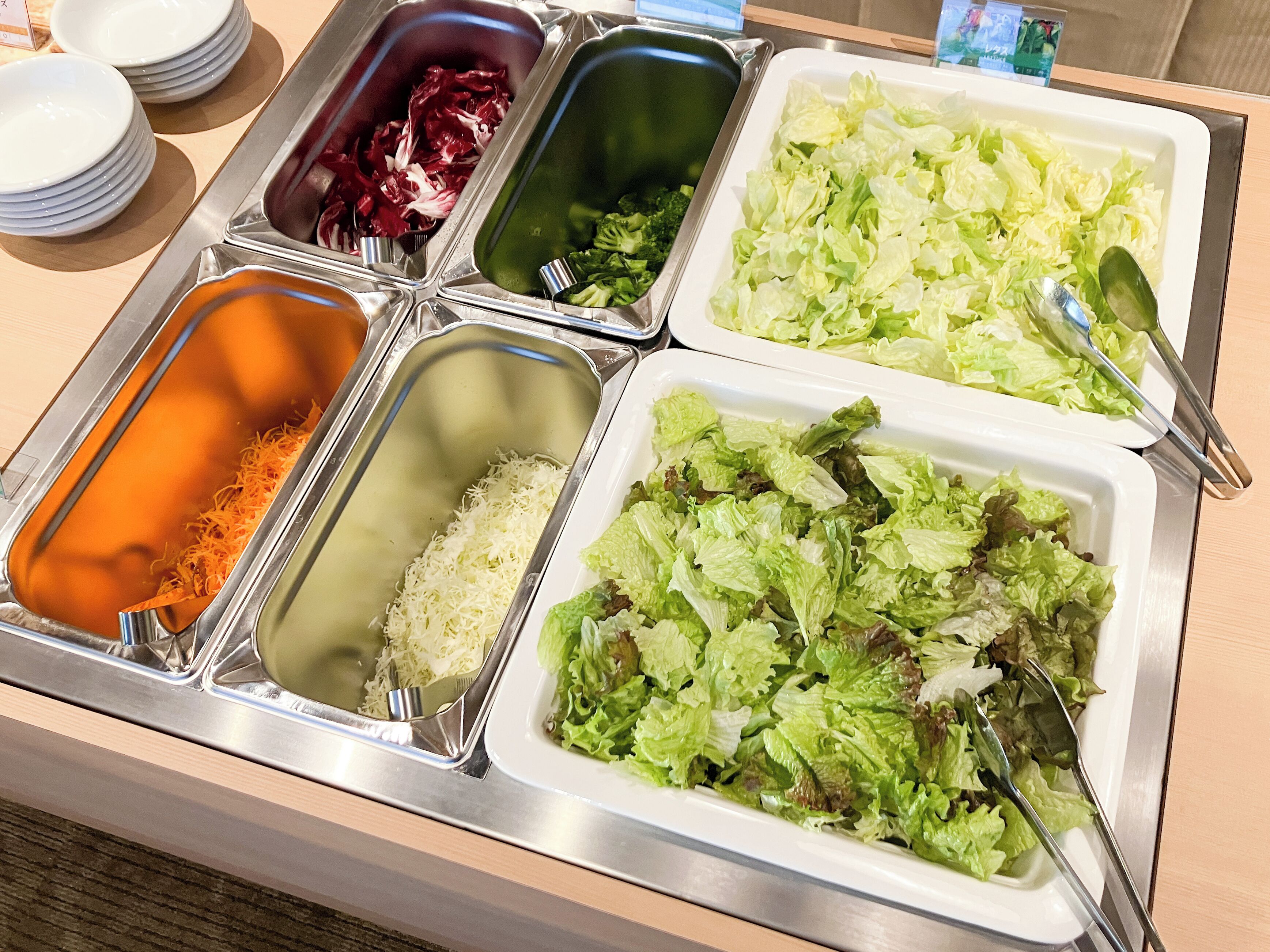 Ein Buffet mit verschiedenen Speisen, darunter geriebenem Käse, Reis und gemischtem Salat.
