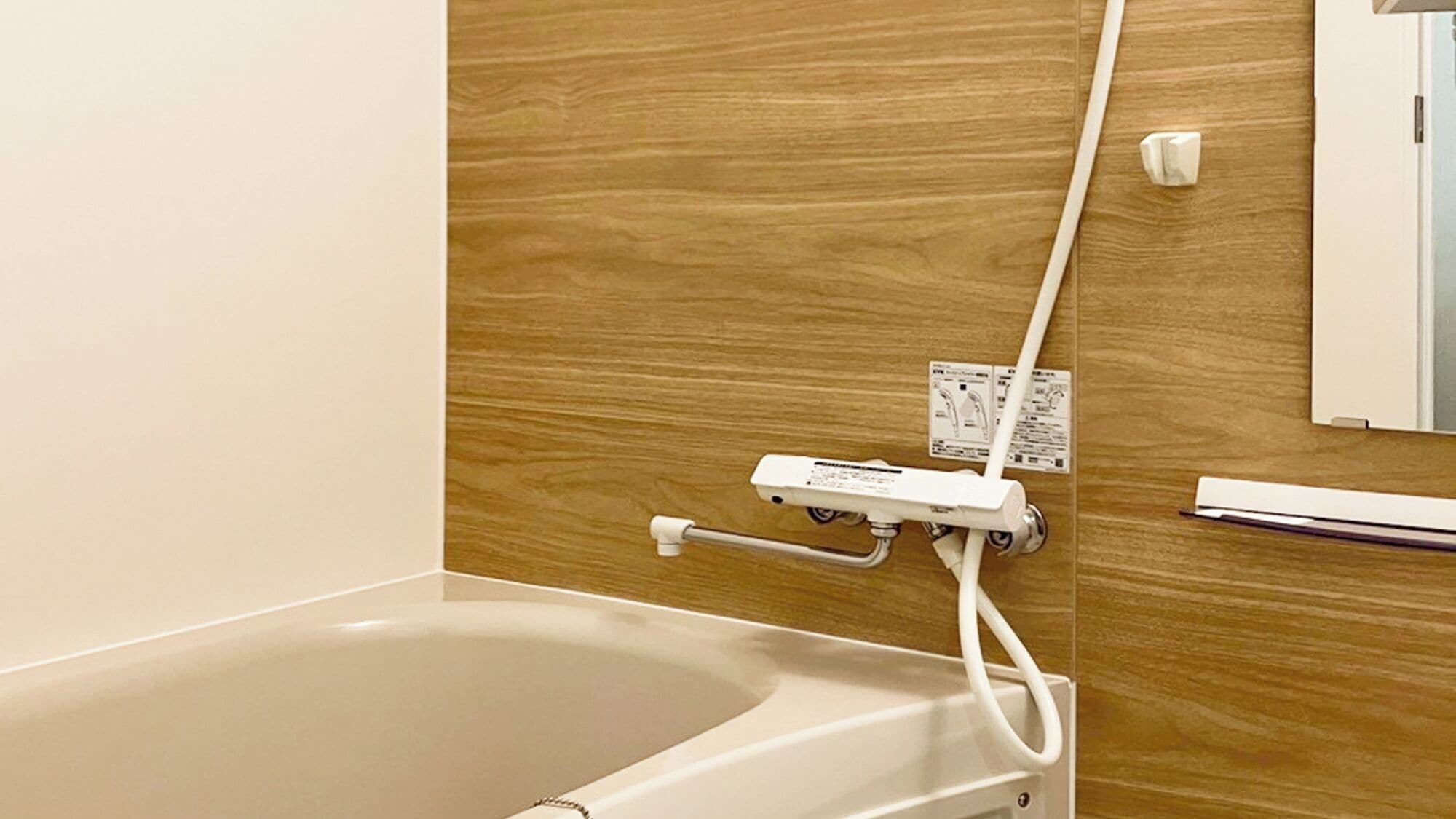 A bathroom with a wooden wall, a white bathtub, and a handrail.