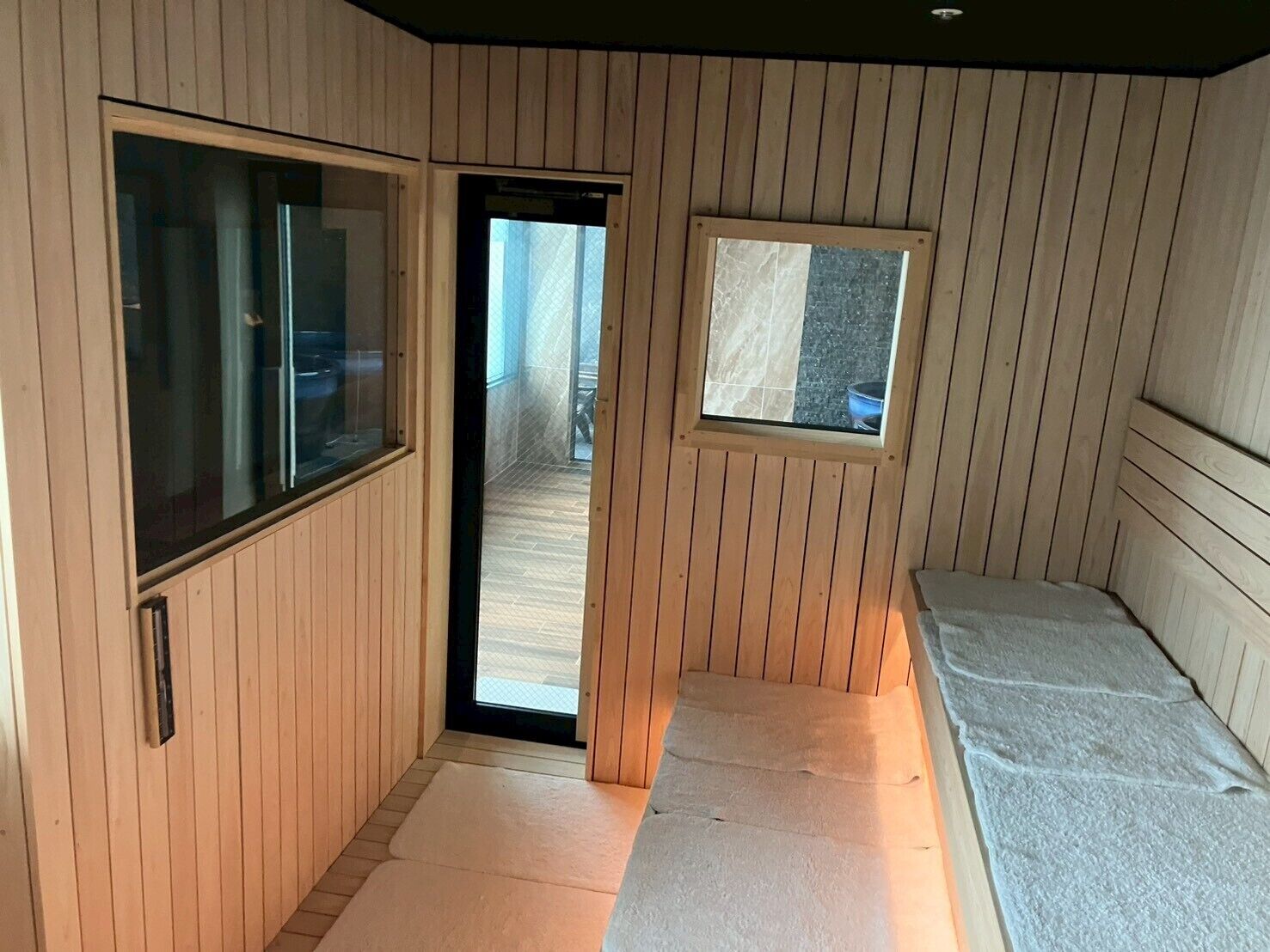 A room with wooden paneling, a sliding door, a small window, and a bed with a mattress.