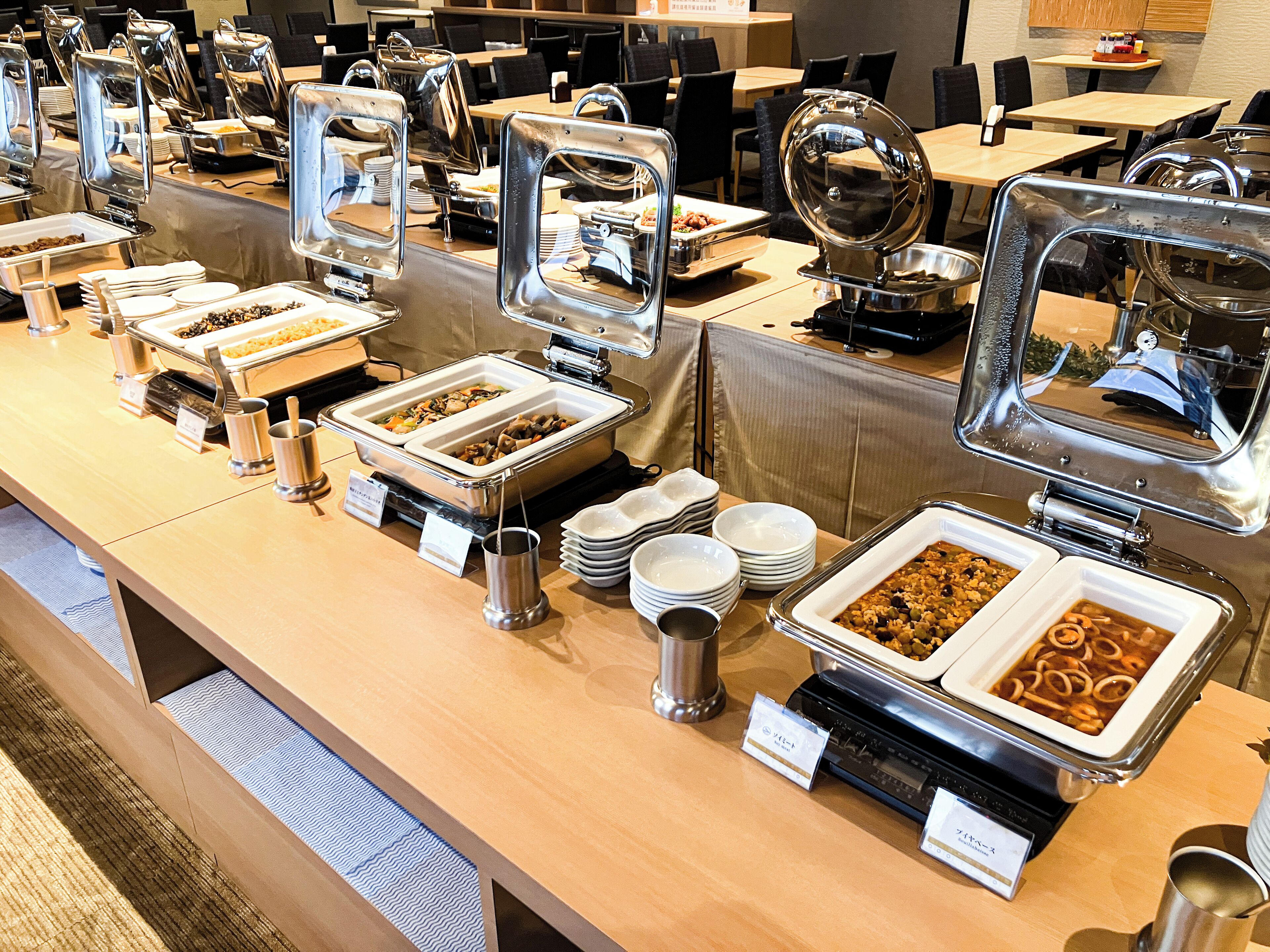 A buffet setup with multiple serving stations, including trays of food and serving utensils.