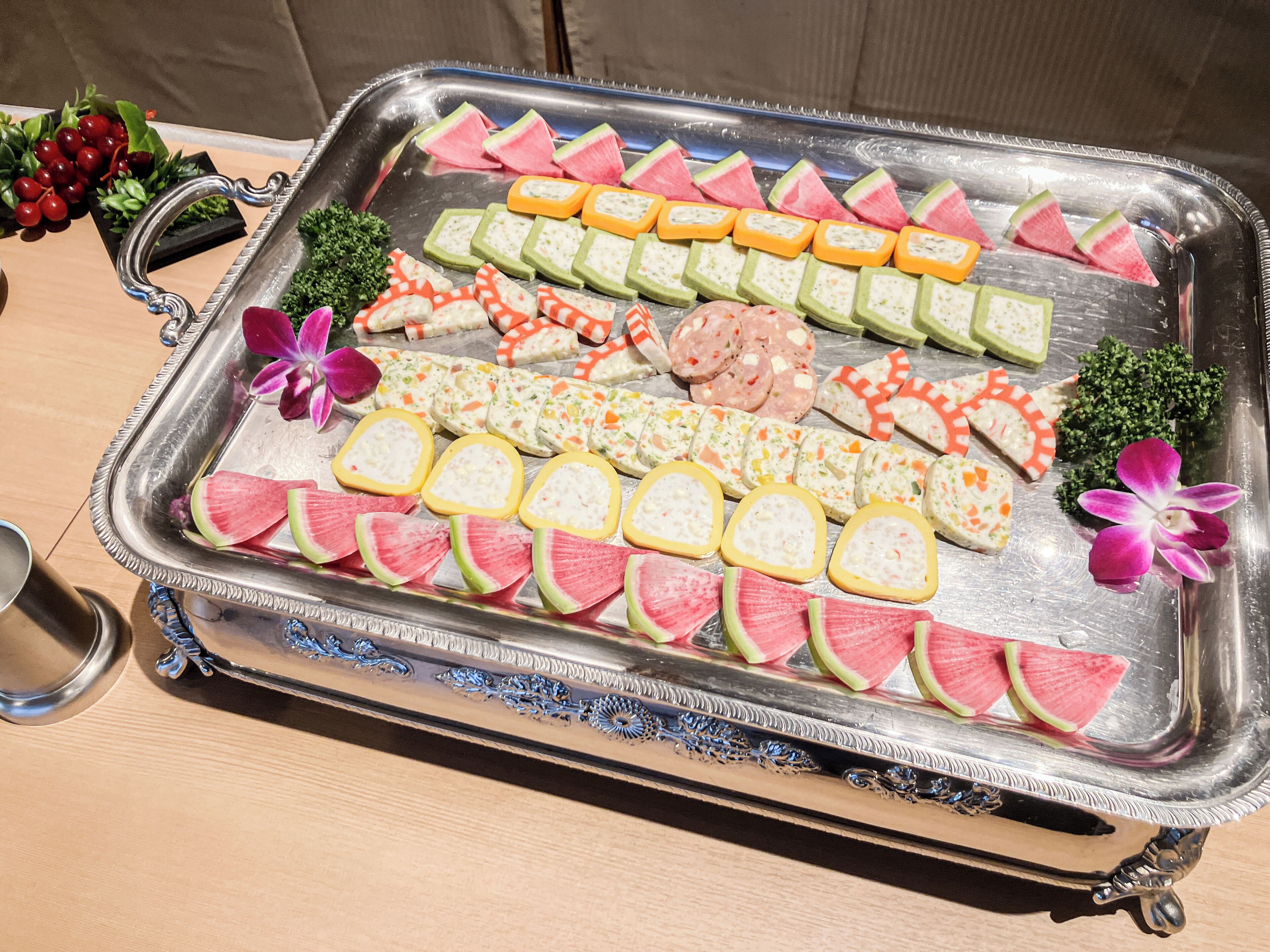 A tray with various food items including watermelon slices, cheese, and other snacks.