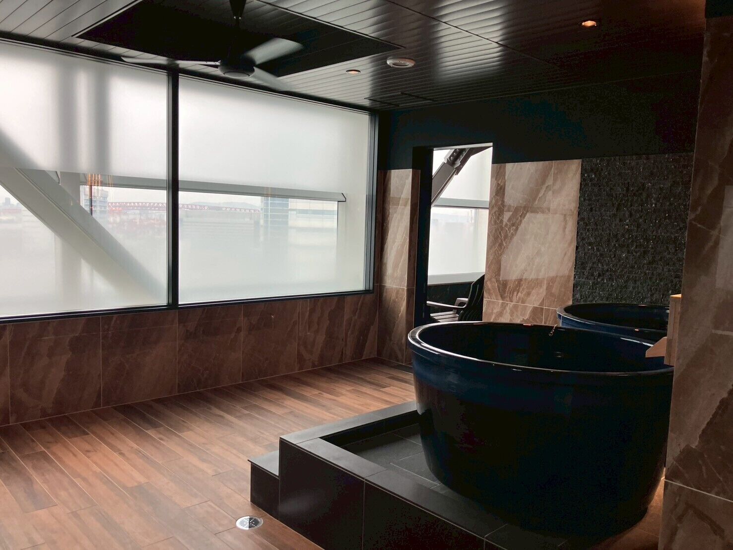 Ein modernes Badezimmer mit einer großen Badewanne, einem Spiegel und Blick auf die Stadt durch große Fenster.