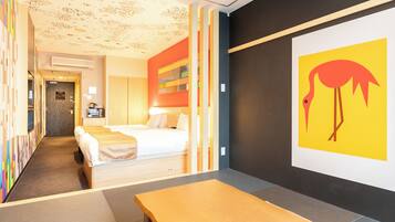 A hotel room with a bed, a desk, and a wall with a colorful painting.