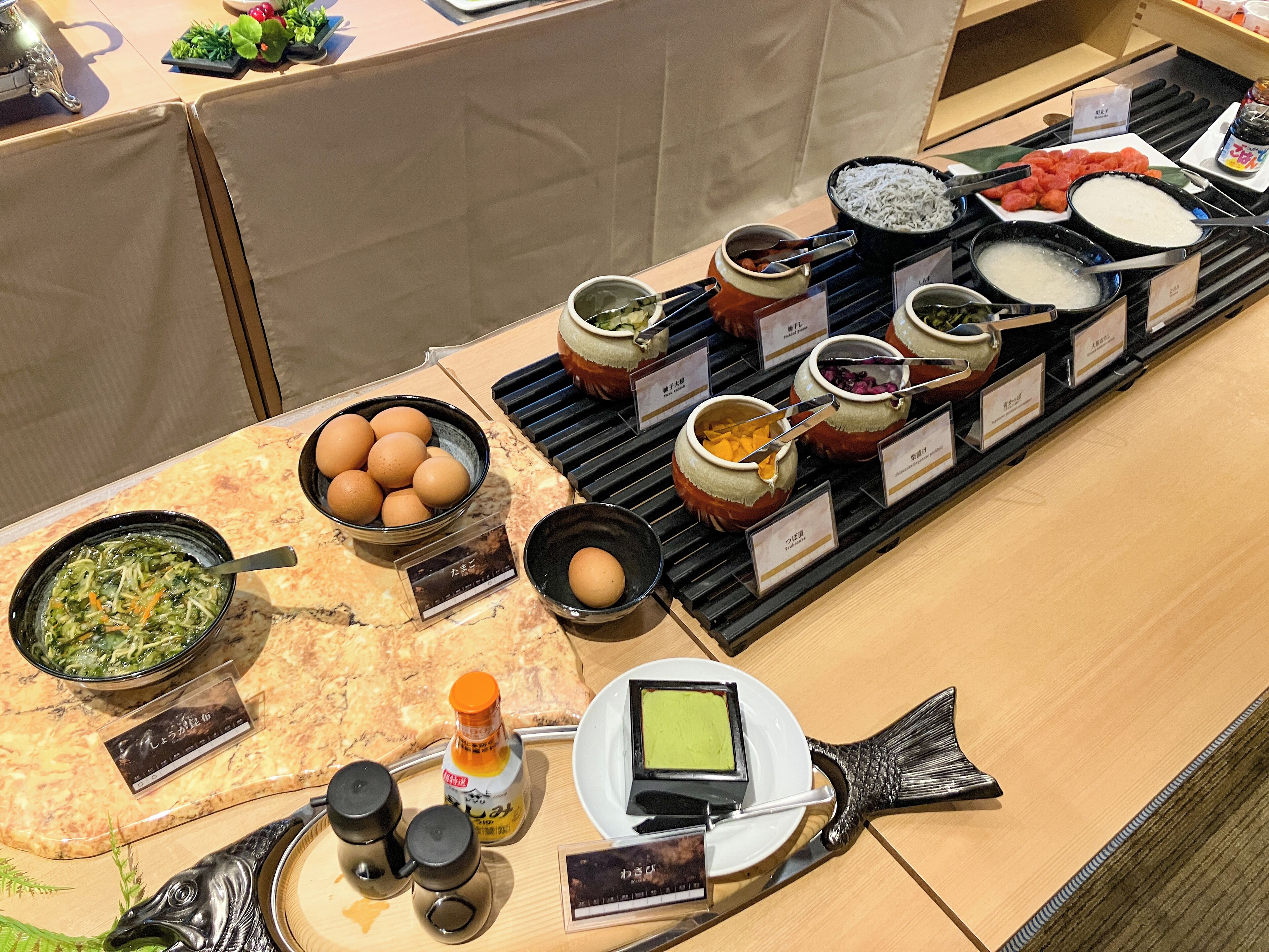 A buffet with various dishes and condiments, including eggs, soup, and rice.