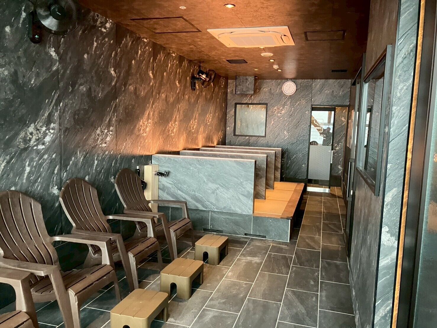 A spa area with wooden chairs, a marble counter, and a tiled floor.