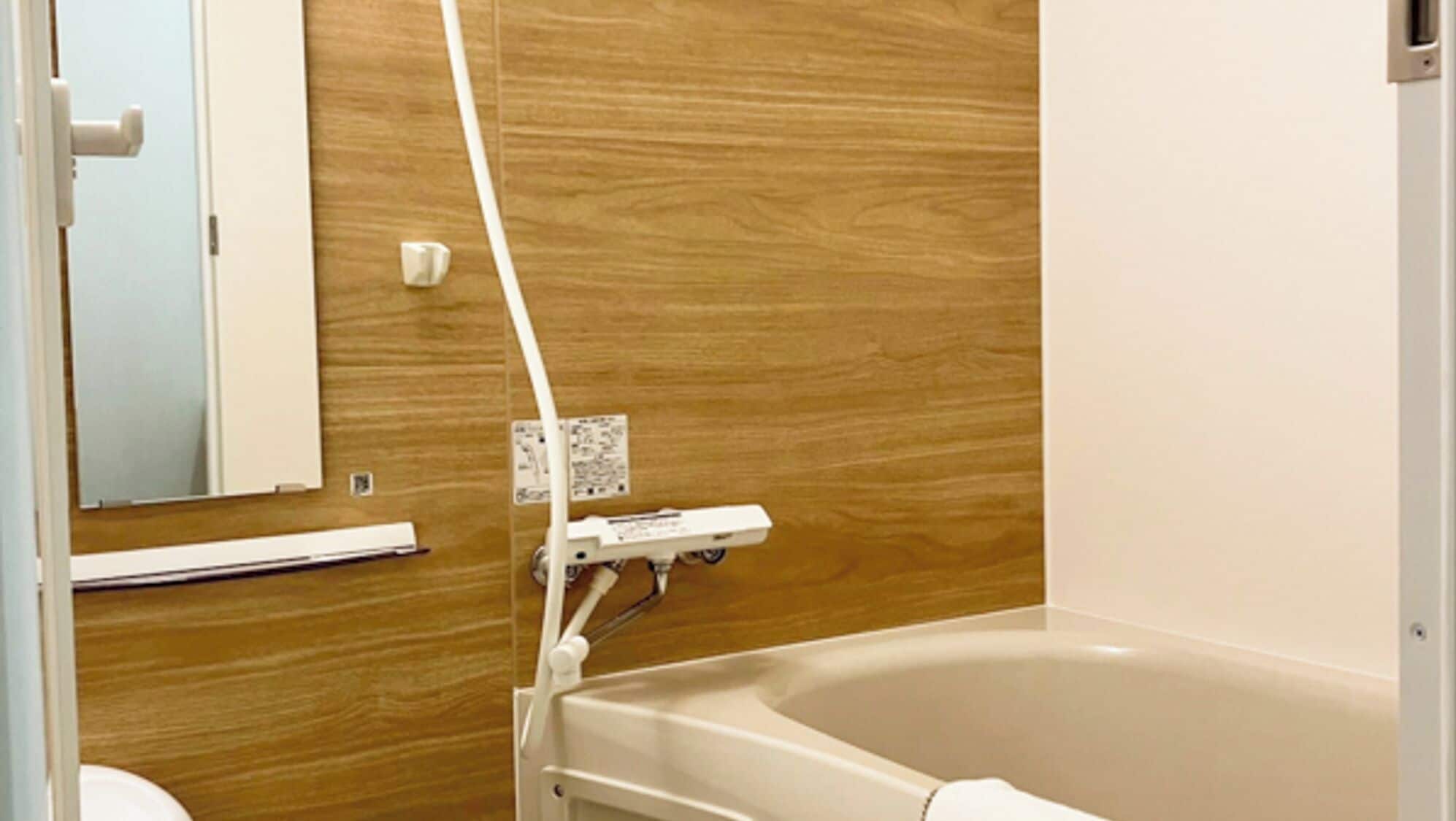 A bathroom with a wooden wall, a white bathtub, and a mirror.