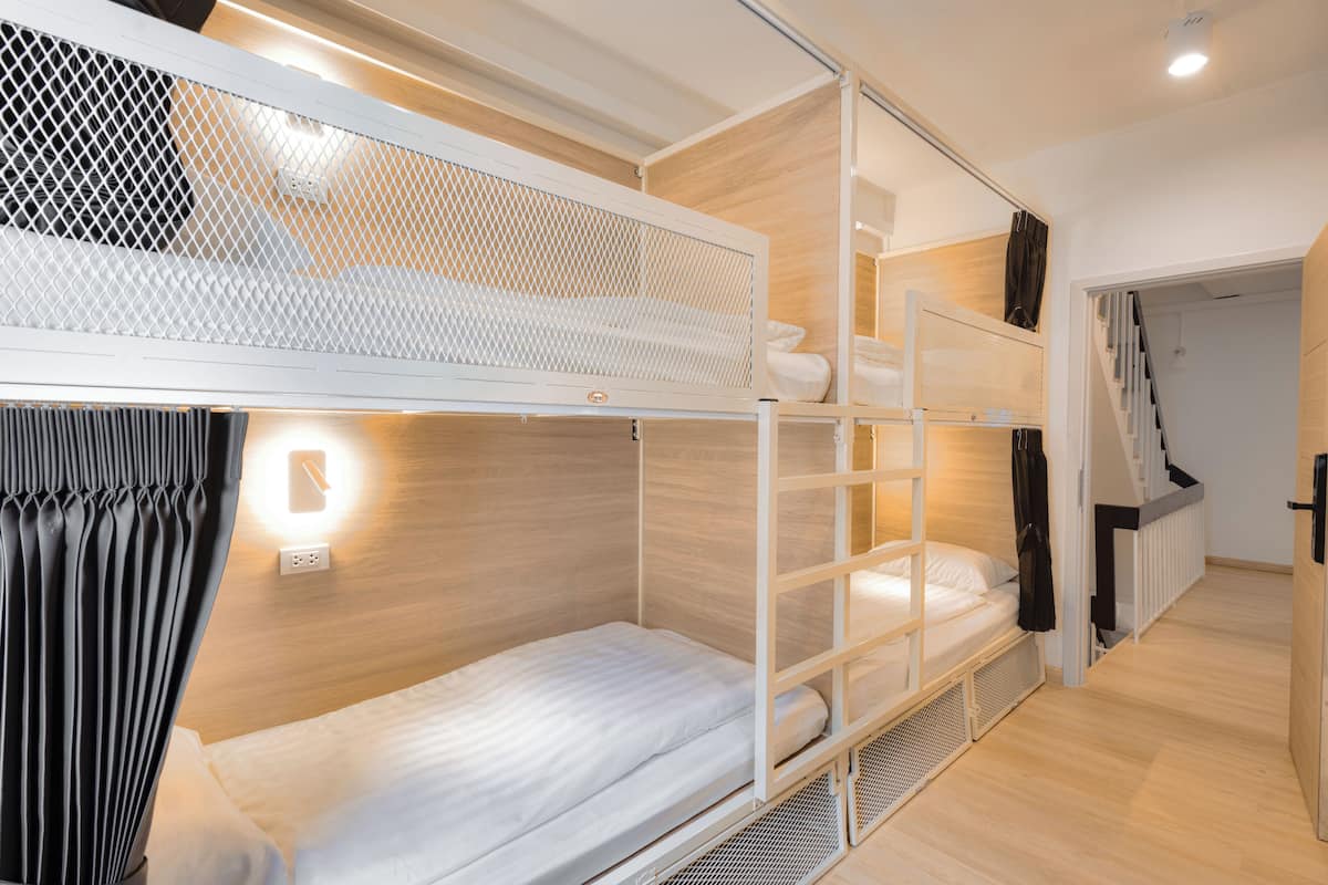 Une chambre avec un lit superposé, une tête de lit blanche, un petit bureau et une armoire.