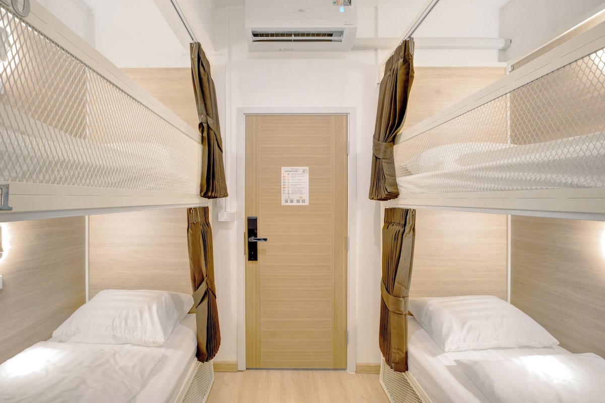 Une chambre d’hôtel avec deux lits superposés, une porte en bois et un mot collé sur la porte.