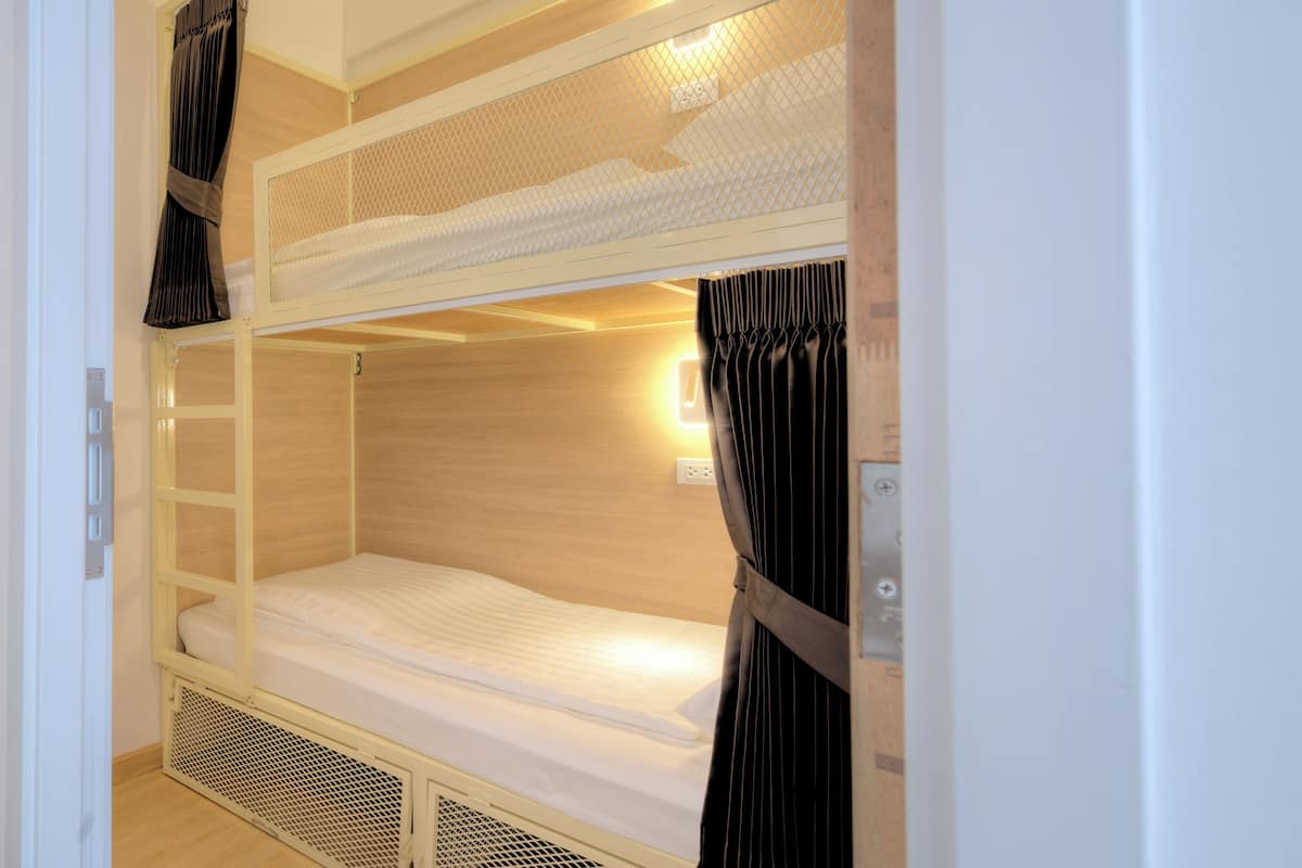 Un lit superposé avec un lit inférieur, une échelle et une tête de lit ornée d’un motif en treillis.