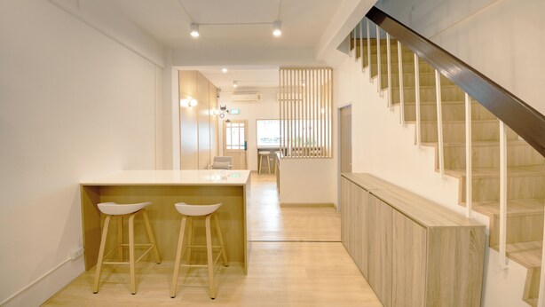 Une cuisine moderne avec un plancher en bois, un îlot central doté de tabourets et un escalier avec des marches en bois et des rampes en métal.