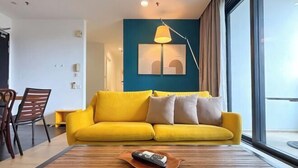 Ein modernes Wohnzimmer mit einem gelben Sofa, einem Holztisch und einer Fernbedienung darauf.