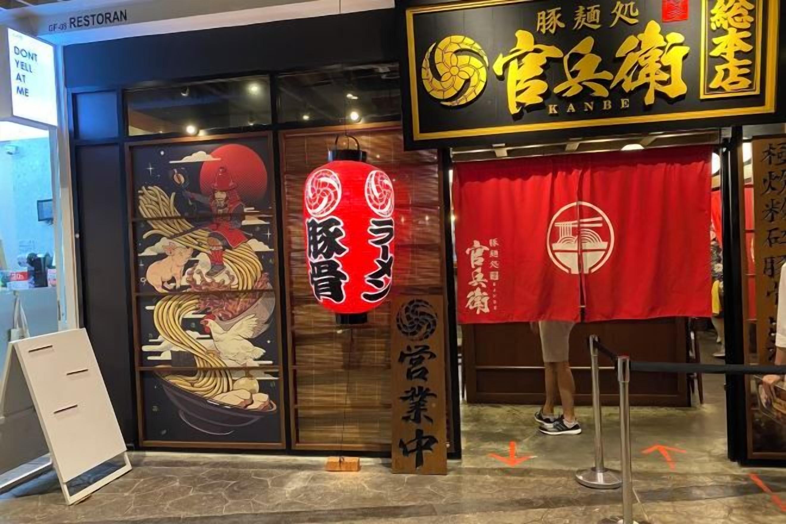 A restaurant entrance with a traditional Japanese design, including a red curtain and a large emblem.