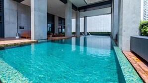 Ein moderner Innenpool mit klarem Wasser, umgeben von Betonstützen und einem Holzboden.