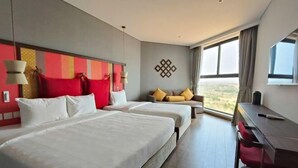 Une chambre d’hôtel avec deux lits, un bureau et une grande fenêtre donnant sur un paysage agréable.