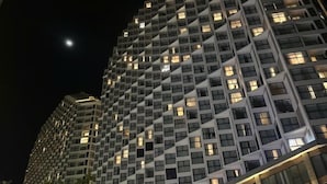 Un immeuble de grande hauteur dont la façade est constituée d’une grille et qui possède de nombreuses fenêtres.