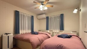 A room with two beds, a ceiling fan, an air conditioner, and a bedside lamp. - Lapis House 201-2F (Tokyo)