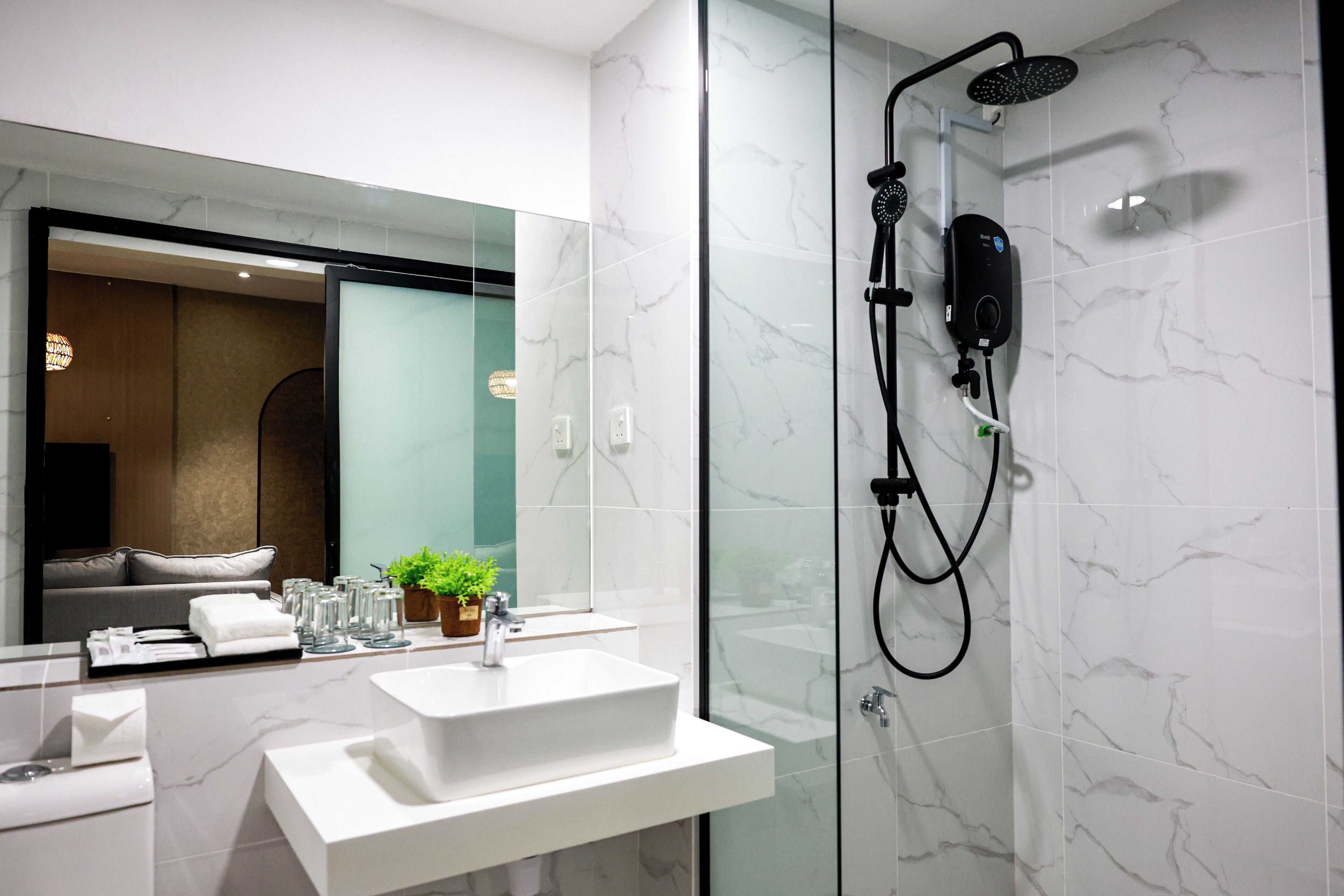A modern bathroom with a glass-enclosed shower, a white sink, and a large mirror.